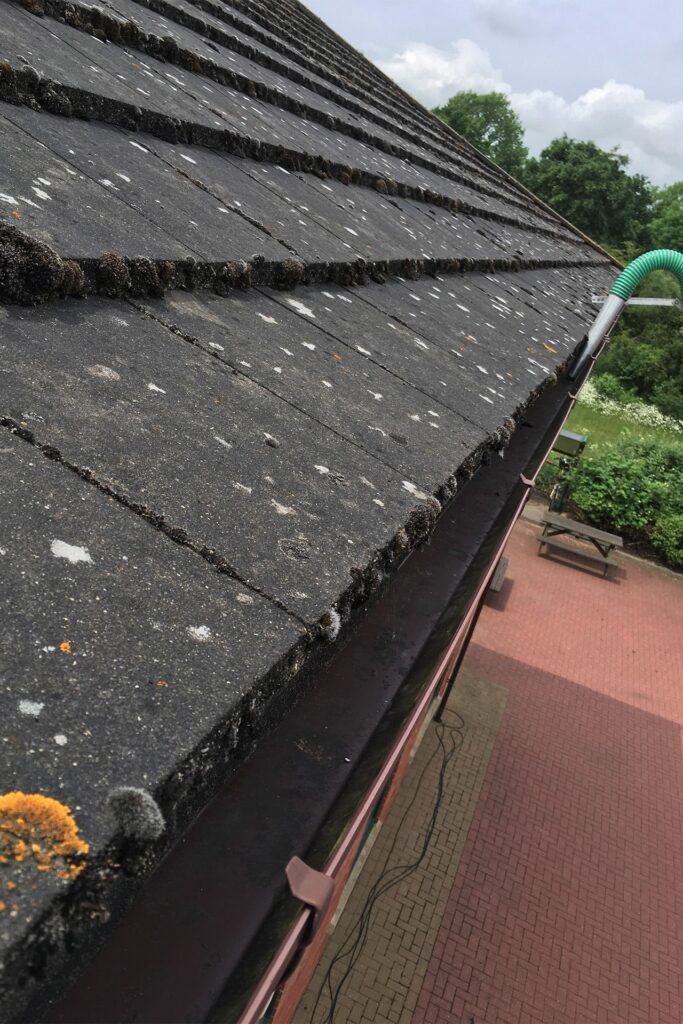 A technician in Leighton Buzzard ensuring gutters are free-flowing at a local school by using a SkyVac gutter vacuum, effectively removing blockages